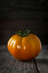 An orange tomato also known as kaki tomato on wooden table