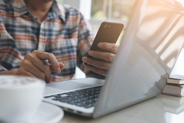 Man working on laptop computer and smartphone at cafe
