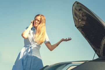 Young and beautiful girl near a broken car with an open hood. Problems with the car, does not start, does not work.