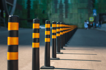 A row of yellow barriers on the road, separating the traffic lines and the pedestrian zone. - obrazy, fototapety, plakaty