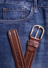 Men's belt and jeans closeup. Belt and jeans closeup. Top view on brown belt and blue jeans.