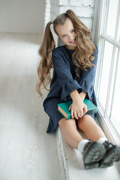 Girl schoolgirl reads a book. School fashion. Fashionable school uniform.
