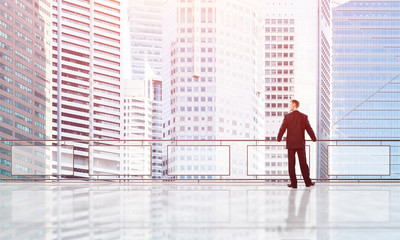 Sunrise above skyscrapers and businessman facing new day