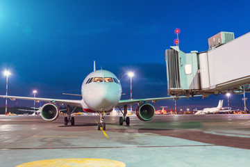 Passenger aircraft arrives at the terminal by night flight, gangway waiting for disembarking...