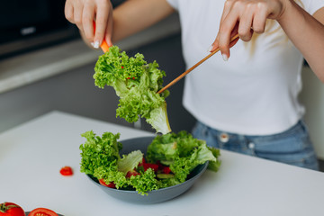 Closeup plate with salad. Female hands mixing salad
