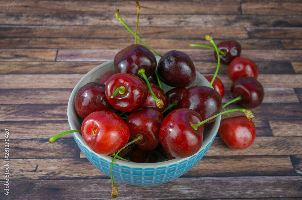 Wall mural fresh sweet cherries in a cup, dark brown wood background with copy space