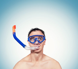 Happy funny man in a swimming mask, with snorkel in his mouth on blue background.