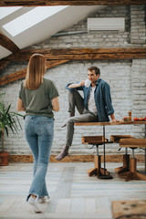 Cute young woman coming into kitchen while man waiting for her