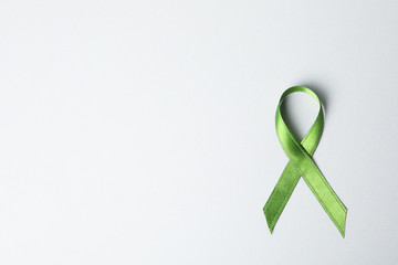 Green awareness ribbon on grey background, space for text