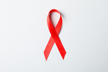 Red awareness ribbon on red background, space for text