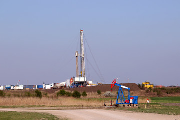 land oil and gas drilling rig and pump jack in oilfield mining industry