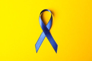 Blue awareness ribbon on yellow background, space for text