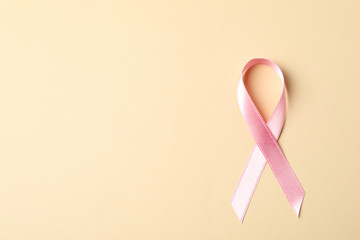 Pink awareness ribbon on color background, space for text