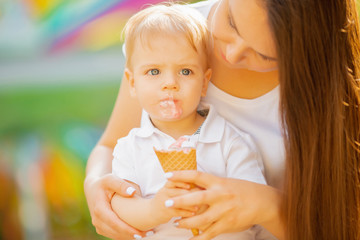Baby boy shares ice cream with mom. Happy family for walk