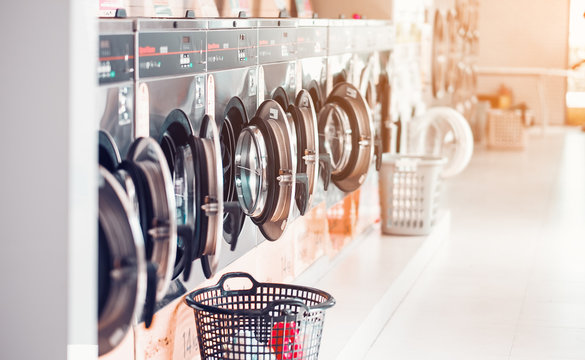 Row of industrial laundry machines in laundromat  in a public laundromat, with laundry in a basket , .Thailand
