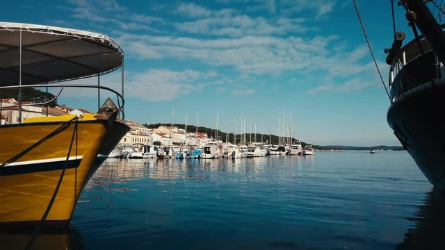 Boats moored in Mali Losinj, Croatia. Peaceful shot of the calm Adriatic sea from the quayside with water reflections on the boats hull.