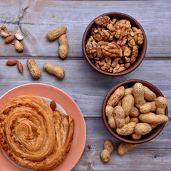 Sweet bun. Heap of Peanuts. Walnuts. Wood background. Top view. Rustic.  Still life.