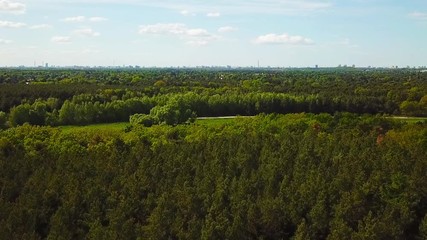 drone aerial footage, flight over a green forest with the city of Berlin far in the back