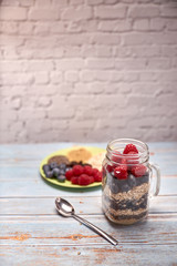 glass jug filled with cereals, raspberries and blueberries