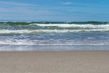 Seaside. A wave is coming. Small grains of sand close up. Concept. Background. Summer is over. Summer sales. Free space for text.