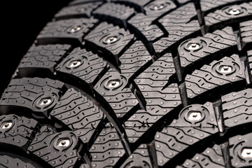 New winter studded tire, safety and premium quality. black background, close-up