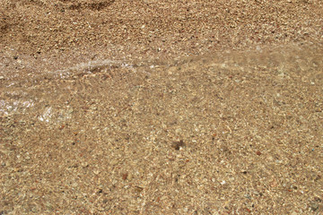 Summer background of hot sand with sea or ocean wave bubbles with copy space for card or advertisement at dawn or sunset