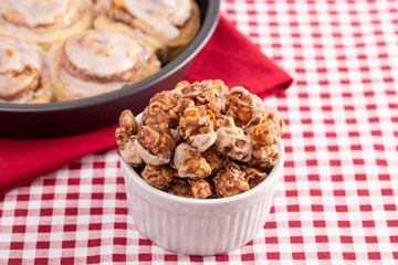 Cinnamon Roll Flavored Gourmet Popcorn on a Red and White Plaid Tablecloth