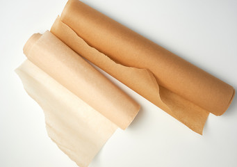 two rolls of brown parchment paper for baking on a white background