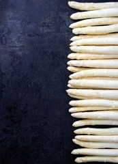 Raw white Asparagus beaded in a row as close-up with copy space left – isolated on black...