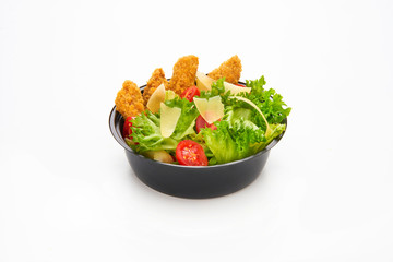 Salad with fried chicken strips and sliced parmesan cheese in a plastic take away bowl on white background