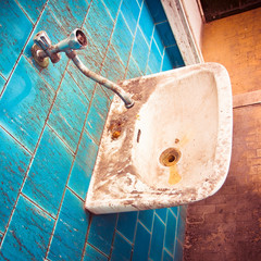 Old sink in a public abandoned restroom - toned image