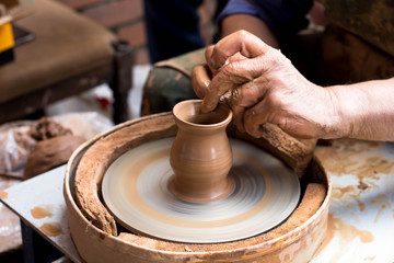 a potter makes a pot of clay on a potter's wheel, hands close up
