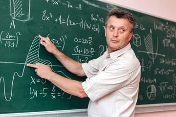Teacher write on the blackboard and explain a lesson showing an example- Image © speed300