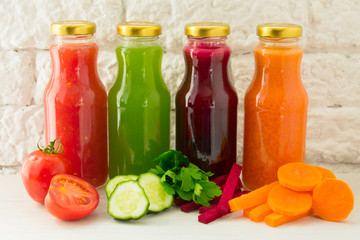  Four vegetable juices in glass bottles. A large plan. The concept of healthy eating.