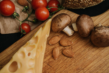 Champignons mushrooms, cherry tomatoes bread and cheese on black background
