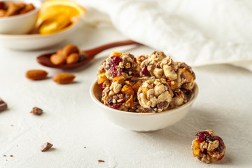 Chocolate, almonds, orange and oatmeal energy balls in white bowl on white background