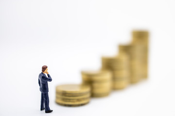 Succession, Finance, Business, Money, Security and Saving Concept. Close up of businessman miniature figures standing and looking tp stack of gold coins on white background and copy space.