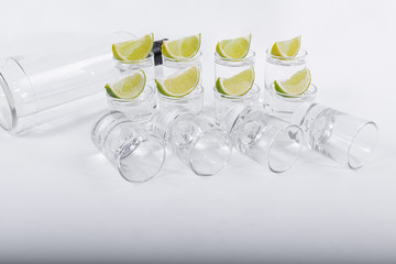 Luxurious tequila served in glasses with lemon slices on top along with a bottle of tequila insulated on a white background