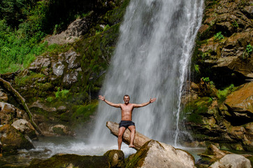 Young man on a waterfall background