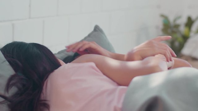 Asian Lesbian lgbtq women couple wake up at home. Young Asia lover female happy relax rest together after sleep all night on bed while lying on bed in bedroom at home in the morning concept.