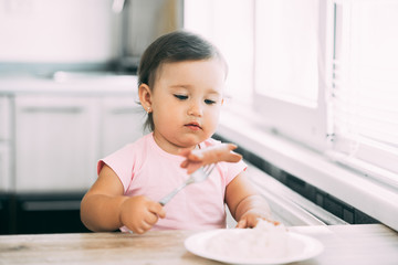 Little baby girl in the kitchen eating sausage and mashed potatoes