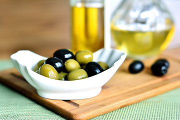 green olives in bowl and olive oil in bottle