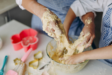 Closeup daughter and mother are stir the dough together and dirty they arms- Image