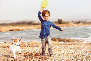 Family leisure activity and fun at fall (autumn) beach - happy kid playing with dog