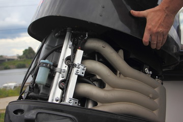 A man's hand closes the hood of a powerful outboard boat motor, repair and maintenance of boat...