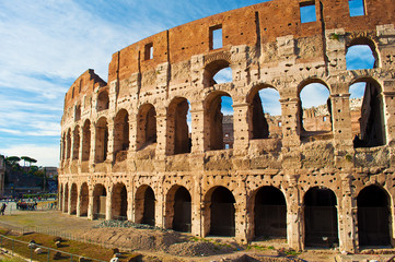Fototapeta premium View of the top of amphitheater of Colosseum against blue sky with wispy clouds