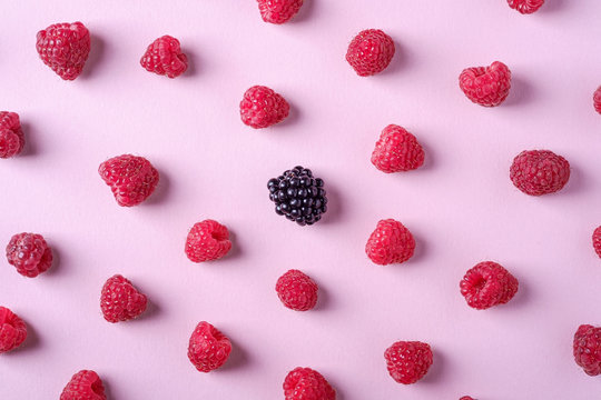 Raspberry sweet organic juicy berries with single blackberry, pattern, texture, on pink paper background, flat lay
