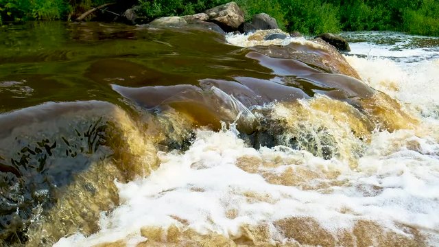 Raging rapids on the river skirts the mountain rocks on both sides. Forming a lot of foam.