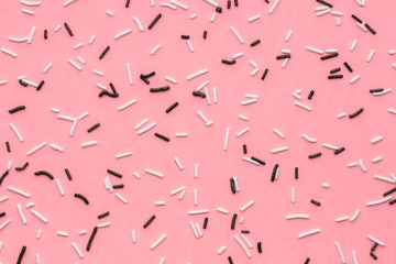 trendy pattern of white and black sprinkles over pink background, sugar sprinkle dots
