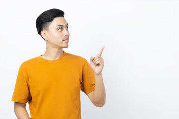 Happy healthy young Asian man smiling with his finger pointing up to copyspace on white background.
